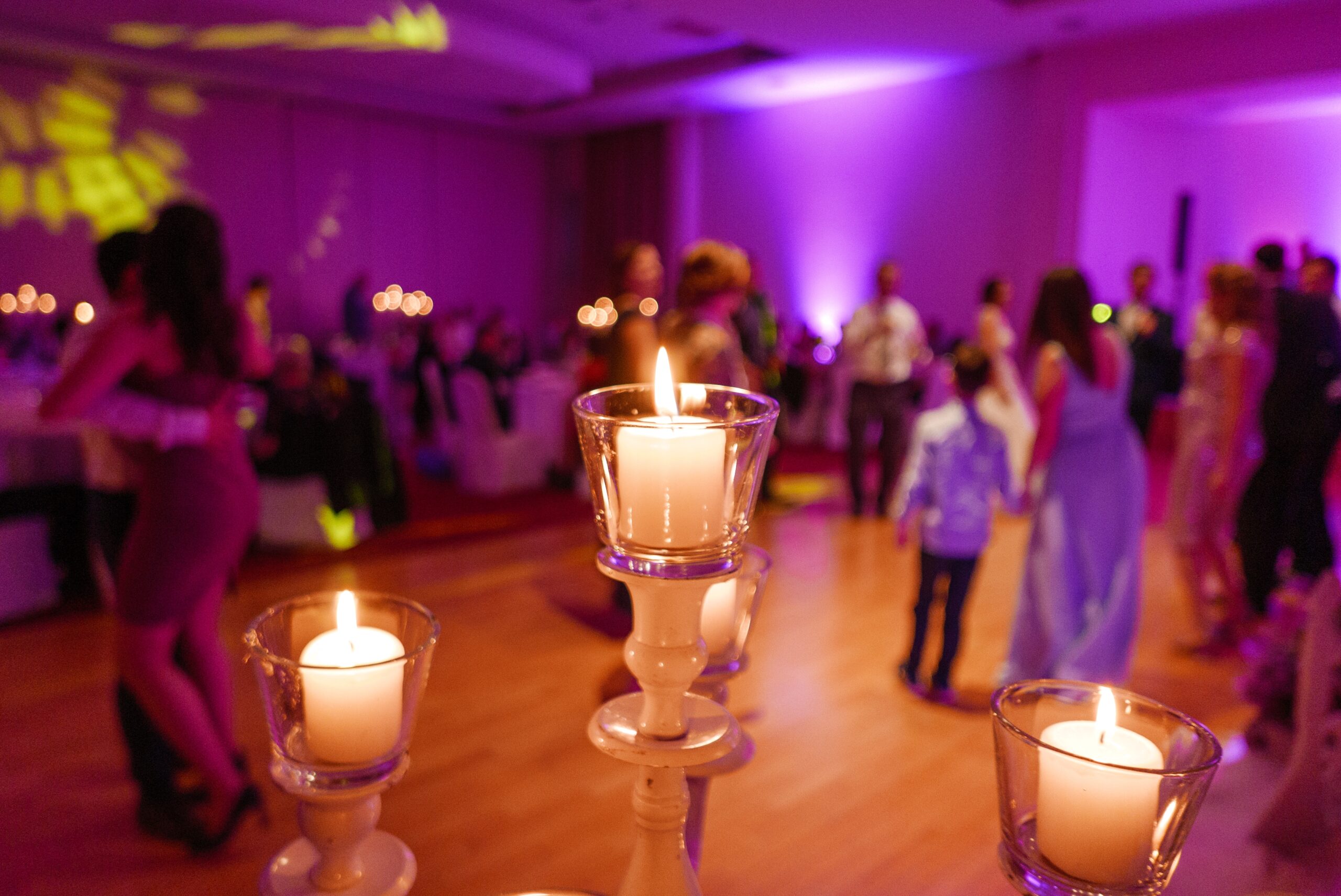 Candles on candle holders illuminating a wedding reception setting