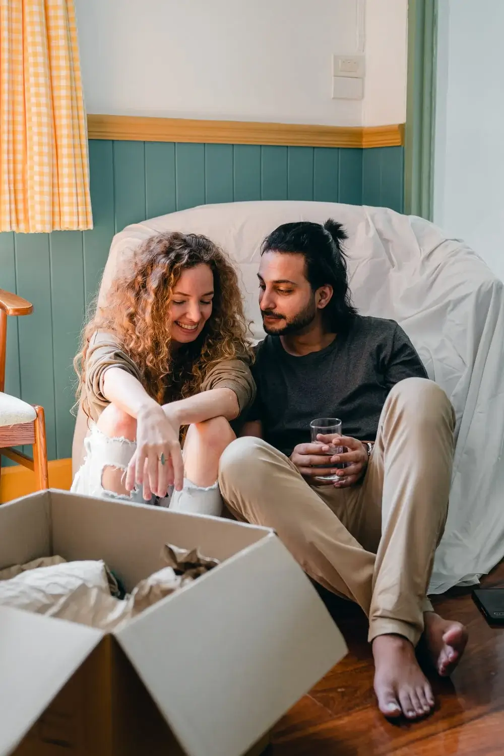 Couple relaxing on a beanbag chair with a moving box, lifestyle guides and home &