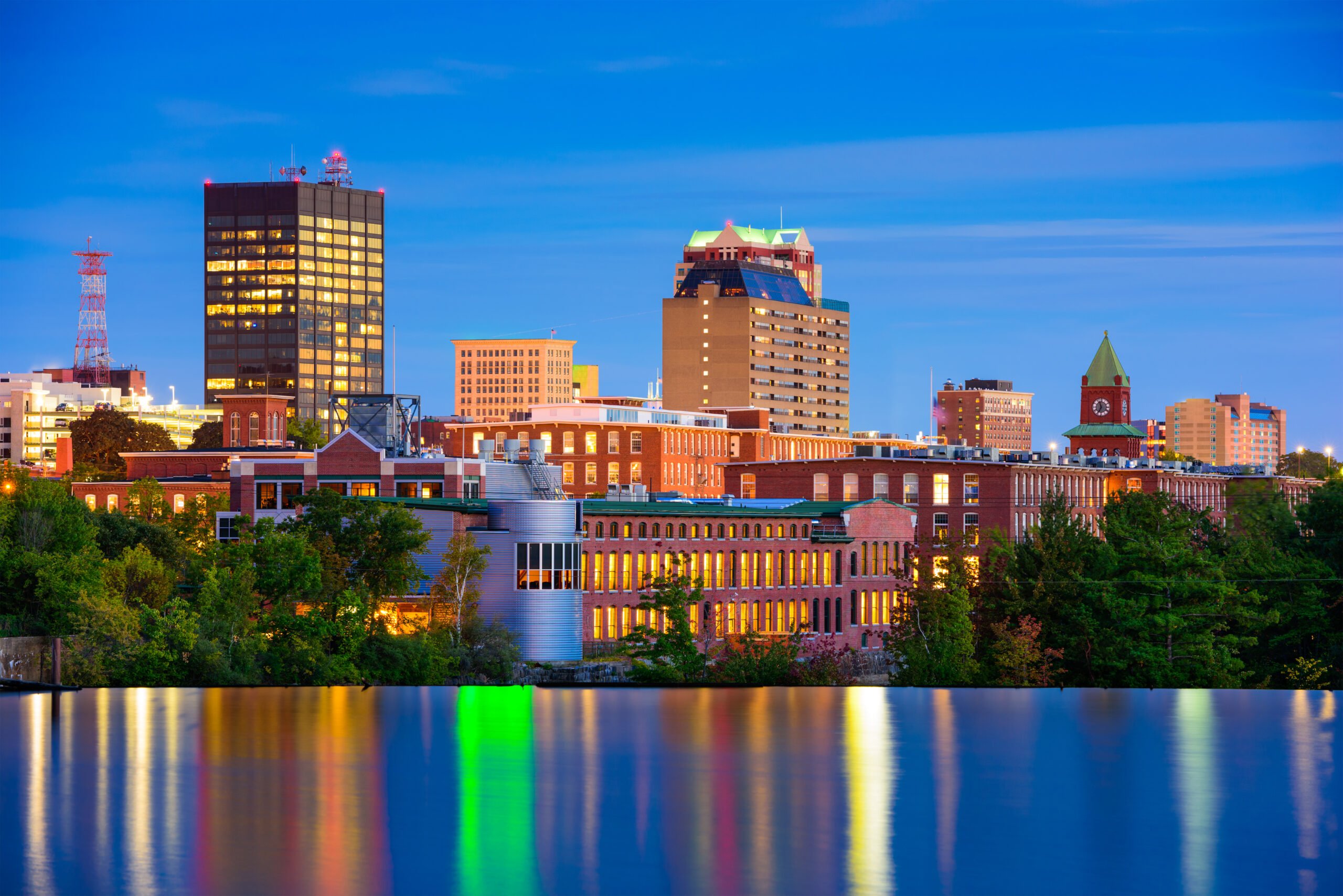 Manchester, New Hampshire skyline at dusk, reflecting in water, travel destination.