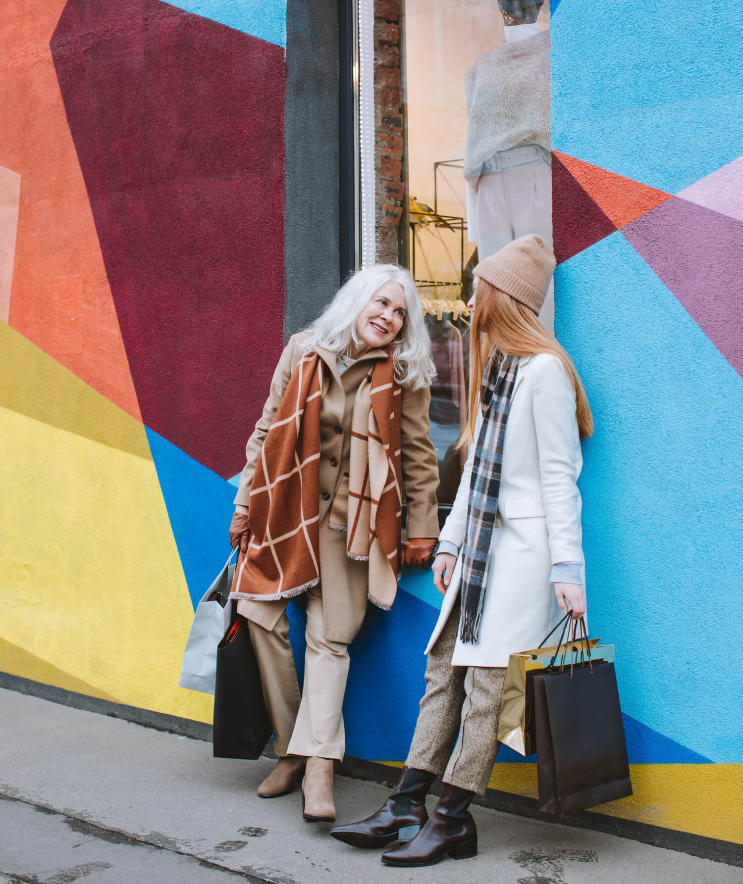 a couple of women walking down a sidewalk with a suitcase